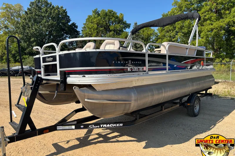 Slide: The Image of 2014 Sun Tracker Fishin' Barge 20 DLX pontoon boat on trailer, parked outdoors. - 2