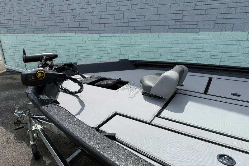 Slide: The Image of 2023 Xpress H17 boat with trolling motor and seating, parked by a textured wall. - 4