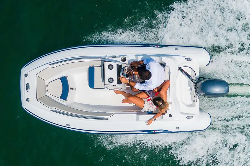 Slide: The Image of 2024 AB Inflatables Nautilus 12 DLX boat interior with white seating and steering console. - 2