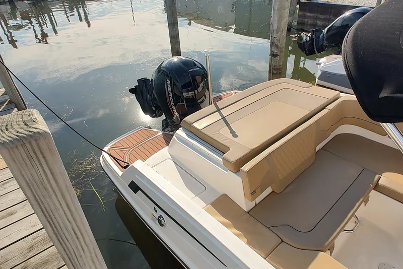 Slide: The Image of 2024 Bayliner VR6 Bowrider OB with tan seating, docked by wooden posts. - 3