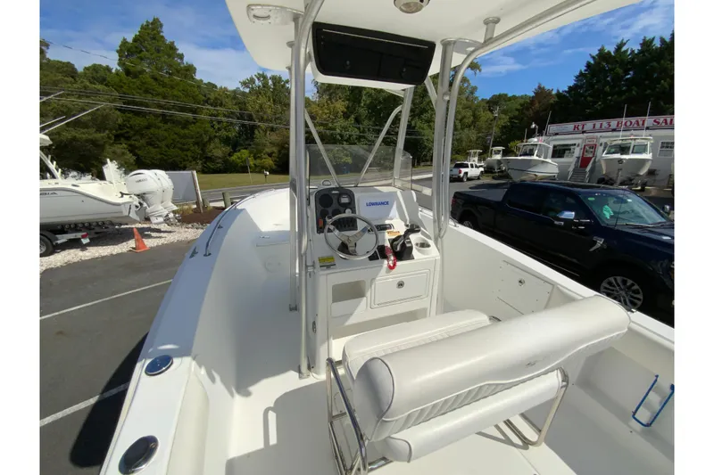 Slide: The Image of 2008 Sea Hunt Triton 220 boat interior with steering console and seating, parked outdoors. - 15