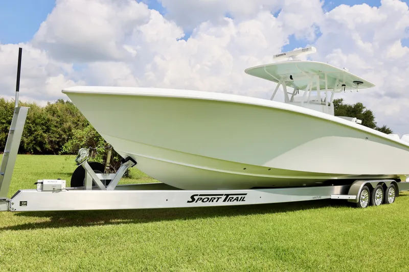 Slide: The Image of 2005 Venture 39 Open boat on Sport Trail trailer, parked on grass under a cloudy sky. - 5