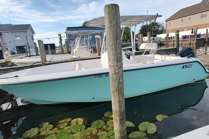The Image of 2023 Twin Vee LFG 22 CC boat docked at marina, turquoise hull, clear sky. - 1