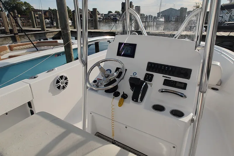 Slide: The Image of 2023 Twin Vee LFG 22 CC boat console with steering wheel and controls at marina. - 8
