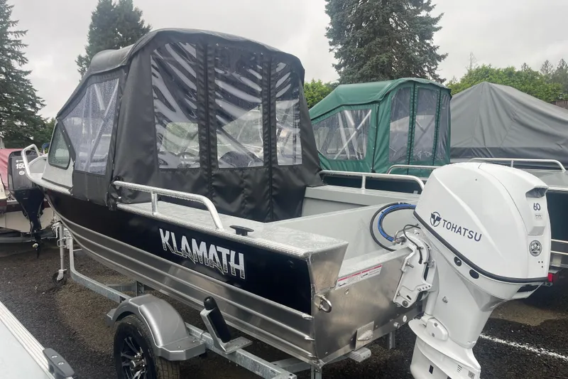 Slide: The Image of 2025 Klamath 18 OPW boat with Tohatsu outboard motor, parked outdoors. - 5