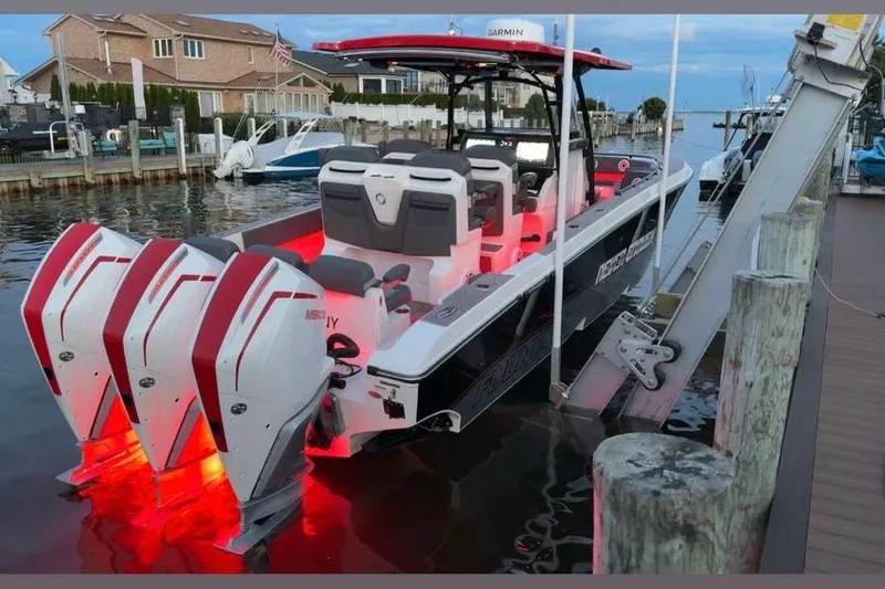 Slide: The Image of 2023 Fountain 34 SC boat with triple Mercury engines, docked with red underwater lights. - 1