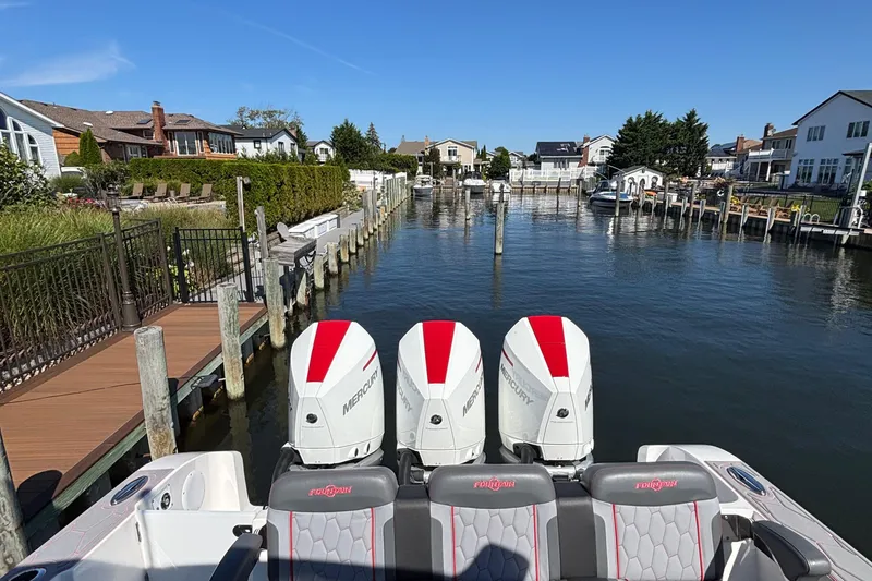 Slide: The Image of 2023 Fountain 34 SC boat with triple Mercury engines docked in a residential canal. - 27