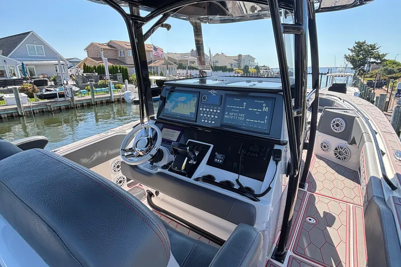 Slide: The Image of 2023 Fountain 34 SC boat cockpit with advanced navigation system, docked in a scenic marina. - 31