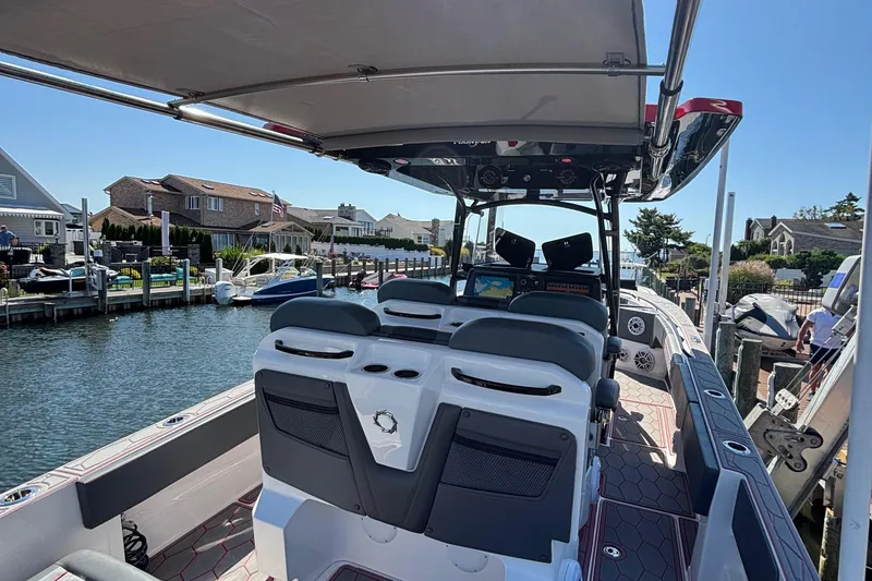 Slide: The Image of 2023 Fountain 34 SC boat interior at a marina, showcasing seating and navigation equipment. - 32