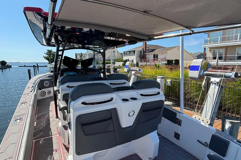 Slide: The Image of 2023 Fountain 34 SC boat interior with seating, docked by waterfront homes. - 33
