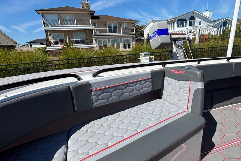 Slide: The Image of 2023 Fountain 34 SC boat interior with hexagonal-patterned seating, docked near waterfront homes. - 39