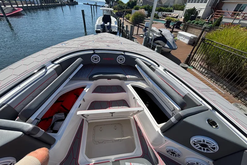 Slide: The Image of 2023 Fountain 34 SC boat interior with open storage, speakers, and seating in a marina setting. - 55