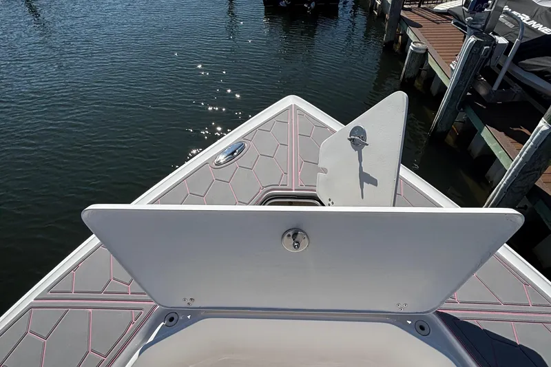 Slide: The Image of 2023 Fountain 34 SC boat deck with open hatch, docked by the water. - 56