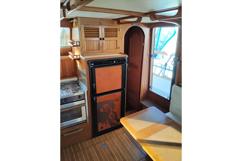 Slide: The Image of 1988 Monk 36 Aft Cabin interior with wood cabinetry, compact kitchen, and dining area. - 22