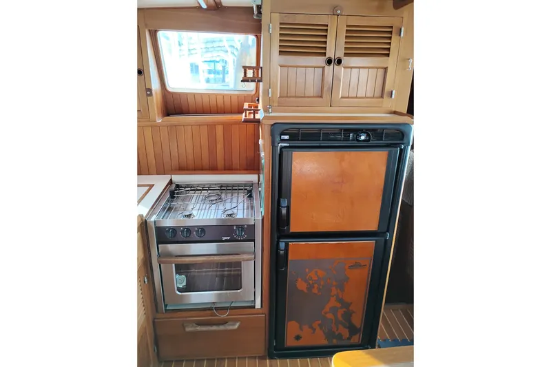 Slide: The Image of 1988 Monk 36 Aft Cabin kitchen with stove, fridge, and wooden cabinetry. - 26