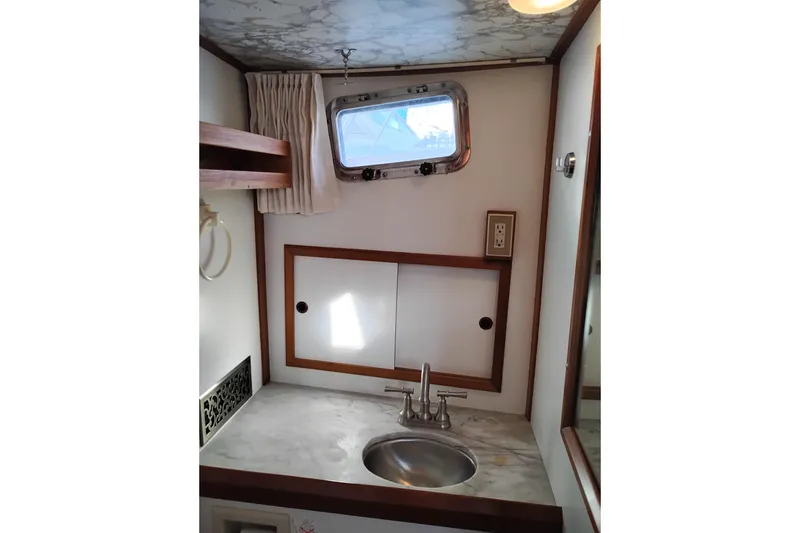 Slide: The Image of 1988 Monk 36 Aft Cabin bathroom with sink, porthole, and marble countertop. - 43