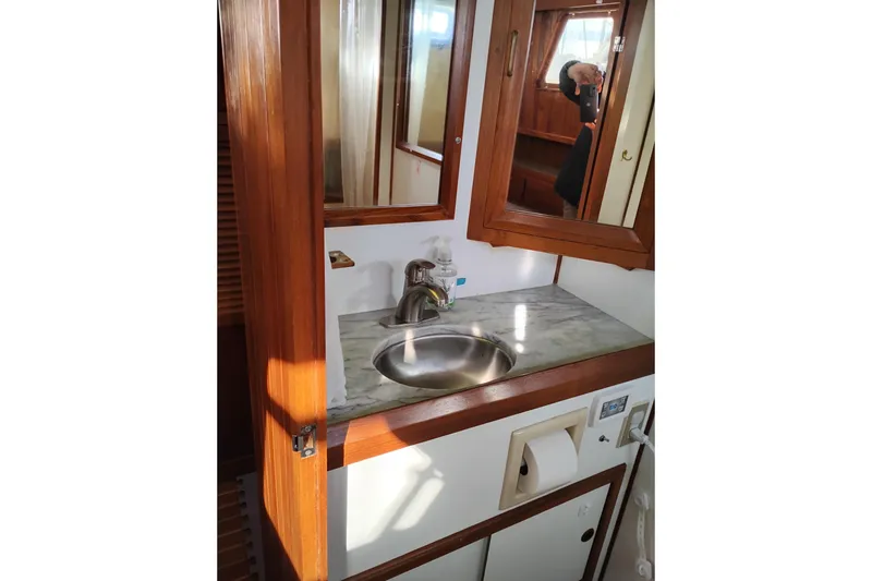 Slide: The Image of 1988 Monk 36 Aft Cabin bathroom with sink, mirror, and wooden cabinetry. - 51