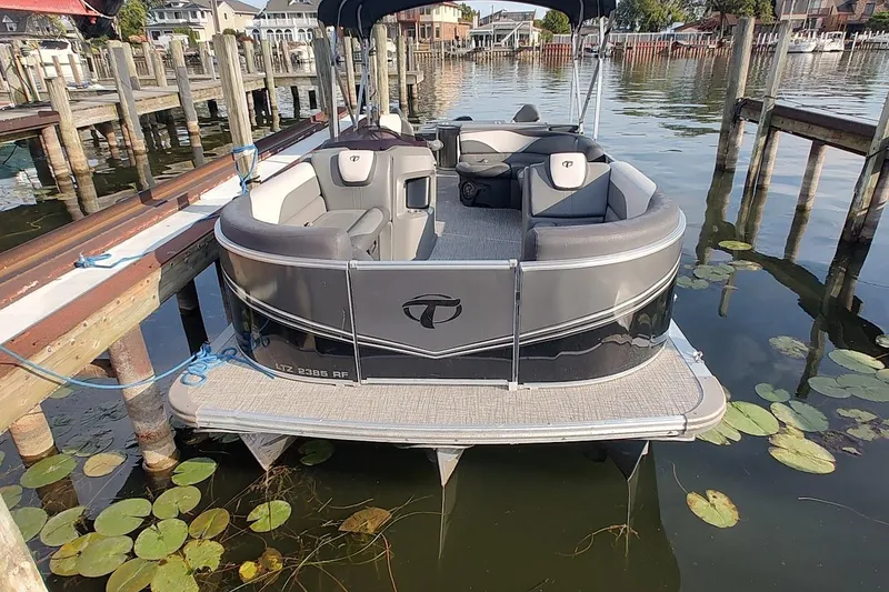Slide: The Image of 2023 Tahoe Pontoon LTZ Entertainer docked on calm water with lily pads. - 3