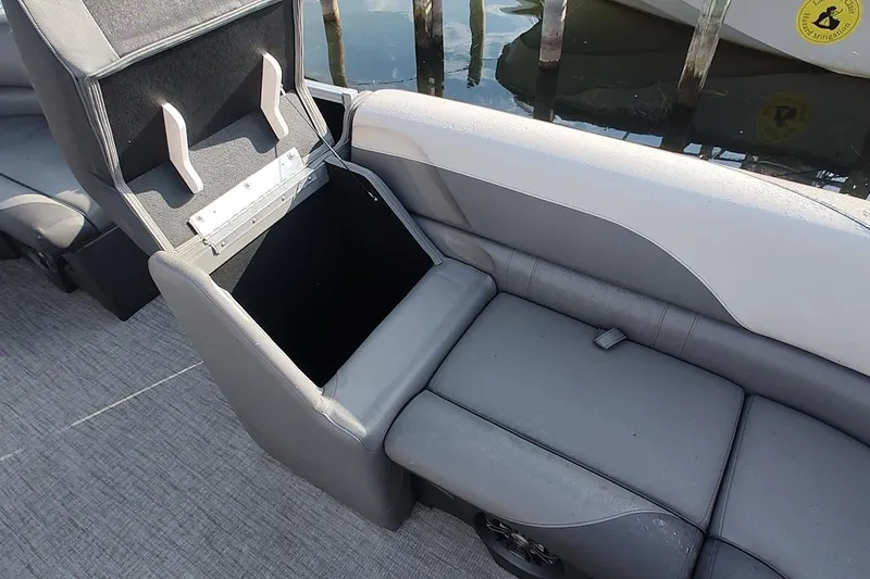 Slide: The Image of 2023 Tahoe Pontoon LTZ Entertainer with open storage compartment on gray seating. - 6