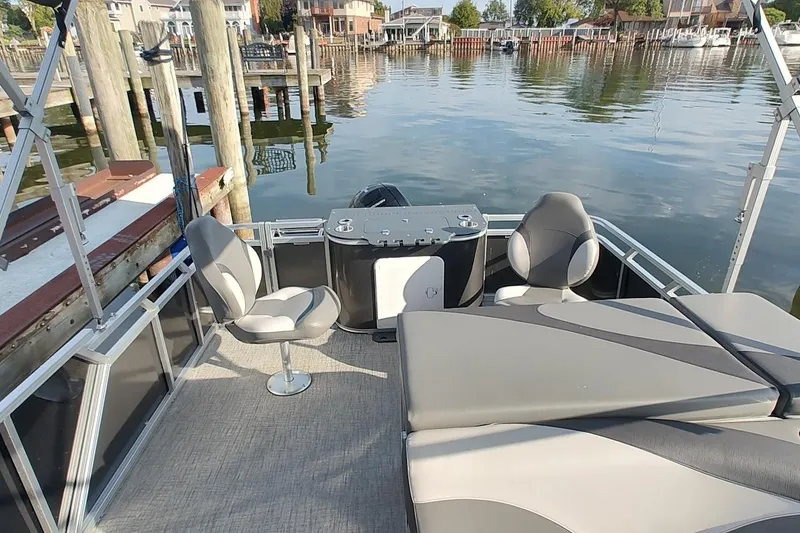 Slide: The Image of 2023 Tahoe Pontoon LTZ Entertainer on calm water, featuring comfortable seating and sleek design. - 7