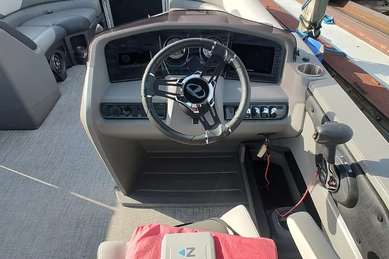 Slide: The Image of 2023 Tahoe Pontoon LTZ Entertainer boat dashboard with steering wheel and controls. - 8