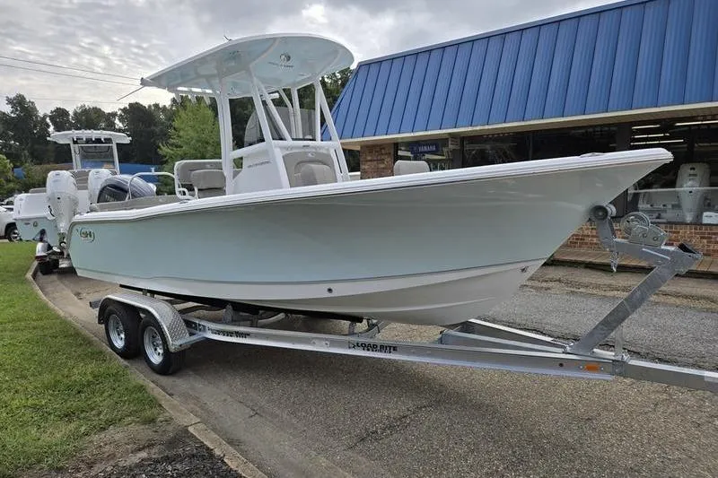 The Image of 2026 Sea Hunt Ultra 229 boat on trailer outside a blue-roofed building. - 2