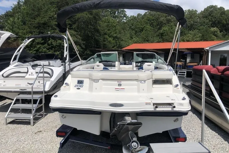 Slide: The Image of 2011 Chaparral 206 SSi boat interior with white seating and dashboard, parked outdoors. - 3
