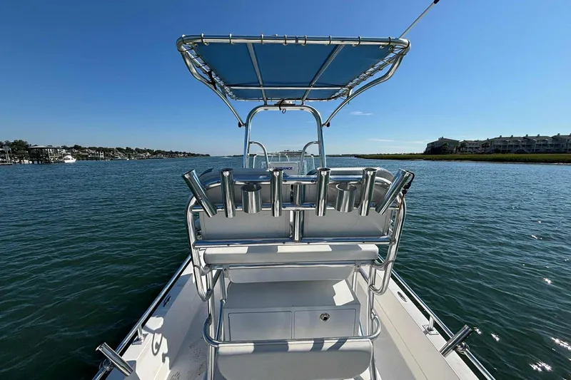 Slide: The Image of 2021 Shallow Sport 24 Modified V boat on calm water, featuring a sleek design and T-top. - 15