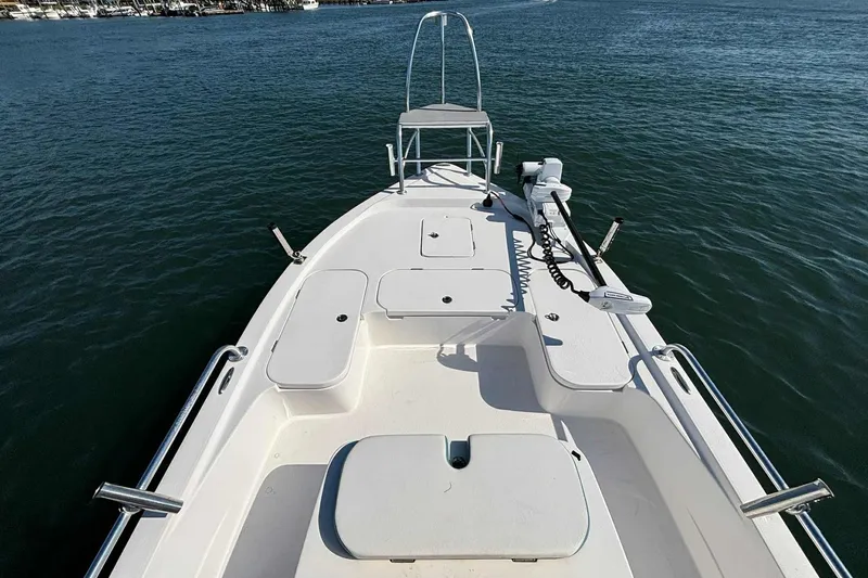 Slide: The Image of 2021 Shallow Sport 24 Modified V boat on calm water, showcasing spacious deck layout. - 18