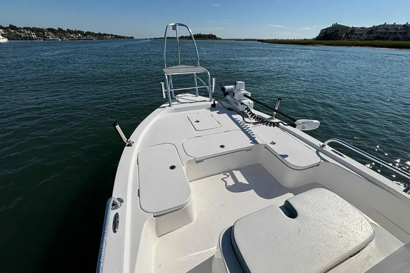 Slide: The Image of 2021 Shallow Sport 24 Modified V boat on calm water, featuring spacious deck and seating. - 19