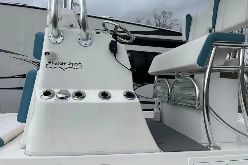 Slide: The Image of 2021 Shallow Sport 24 Modified V boat on water, with person steering, surrounded by greenery. - 7