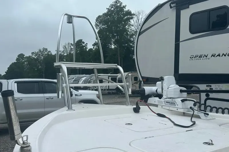 Slide: The Image of 2021 Shallow Sport 24 Modified V boat on water, with person steering, surrounded by greenery. - 8