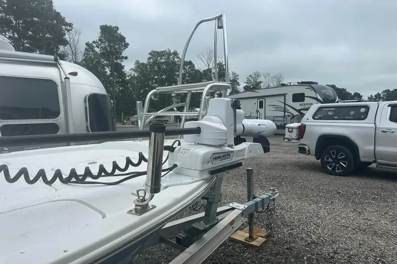 Slide: The Image of 2021 Shallow Sport 24 Modified V boat cruising on a calm lake with lush greenery. - 9