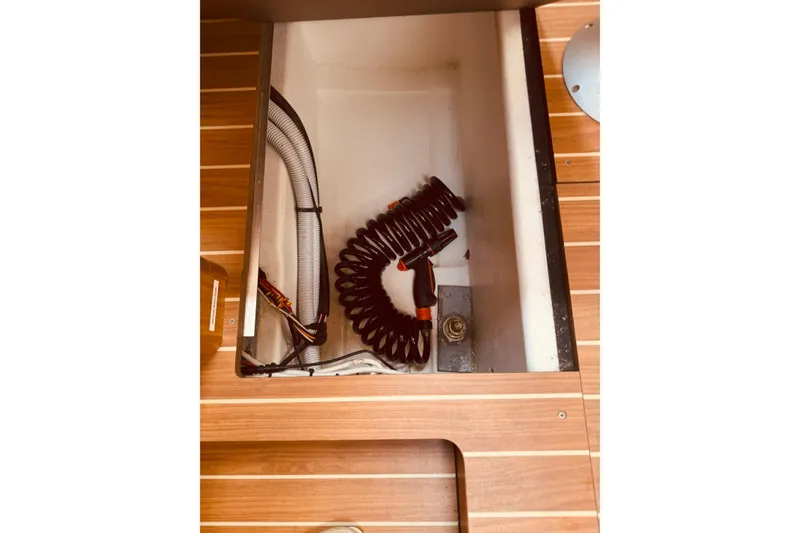 Slide: The Image of Storage compartment on 2008 Jeanneau Sun Odyssey 45 DS sailboat with coiled hose and wooden flooring. - 53