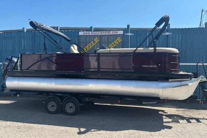 Slide: The Image of 2024 Godfrey SWEETWATER 2286 SFL pontoon boat on trailer, parked outdoors. - 2