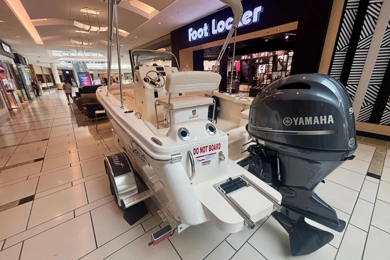 Slide: The Image of 2026 Scout 188 Sportfish boat displayed indoors near Foot Locker store. - 2