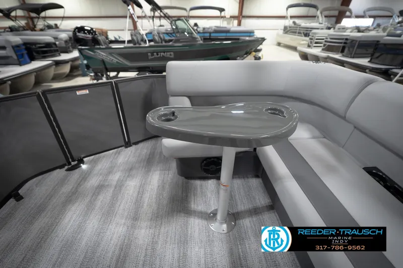 Slide: The Image of 2026 Bennington 21 SL pontoon boat interior with gray seating and table in showroom. - 18