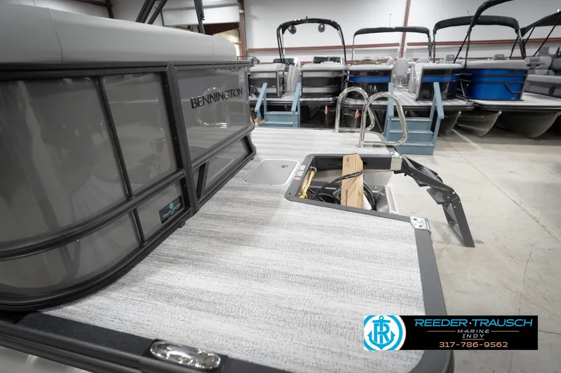 Slide: The Image of 2026 Bennington 21 SL pontoon boat in showroom, featuring open storage compartment. - 61