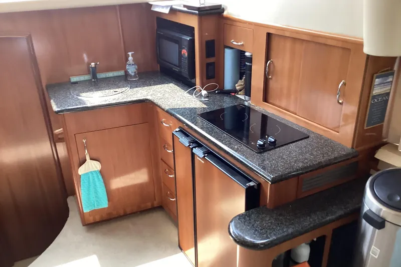 Slide: The Image of 2005 Carver 41 Cockpit Motor Yacht kitchen with stove, microwave, and compact fridge. - 15