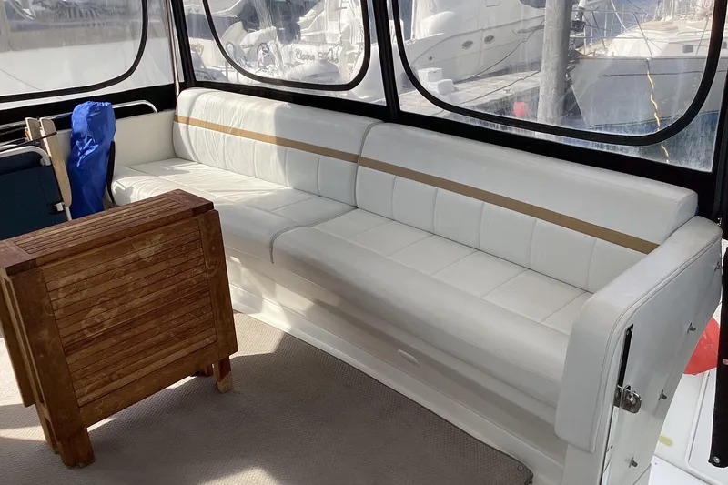 Slide: The Image of 2005 Carver 41 Cockpit Motor Yacht interior with white seating and wooden table. - 23