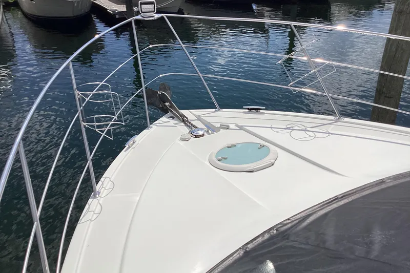 Slide: The Image of 2005 Carver 41 Cockpit Motor Yacht bow with anchor and railing, docked on calm water. - 29
