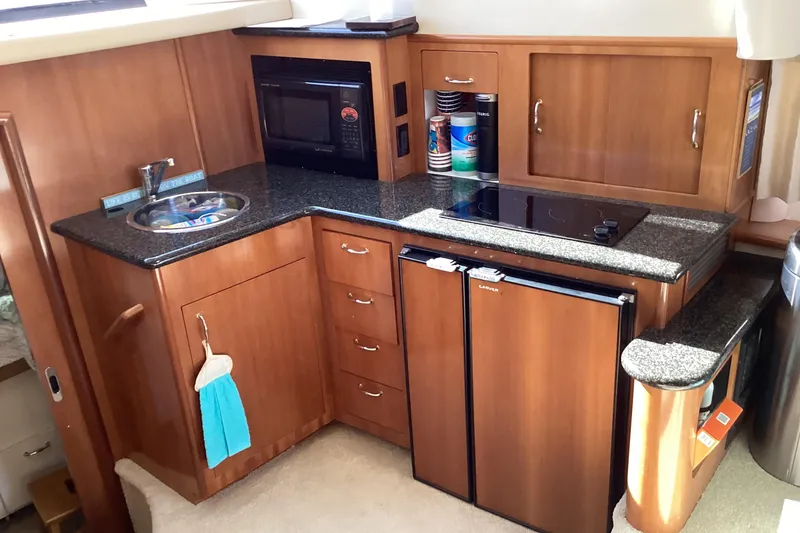 Slide: The Image of 2005 Carver 41 Cockpit Motor Yacht kitchen with wood cabinetry, microwave, and compact fridge. - 34