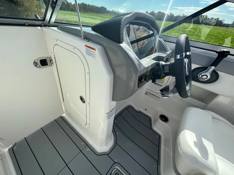 Slide: The Image of 2024 Chaparral 23 SSi boat interior, featuring steering wheel and storage compartment. - 15