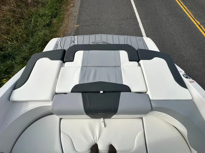 Slide: The Image of 2024 Chaparral 23 SSi boat interior with gray and white seating on a road. - 40