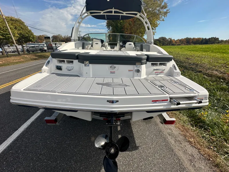 Slide: The Image of 2024 Chaparral 23 SSi boat rear view on a road with green fields. - 49