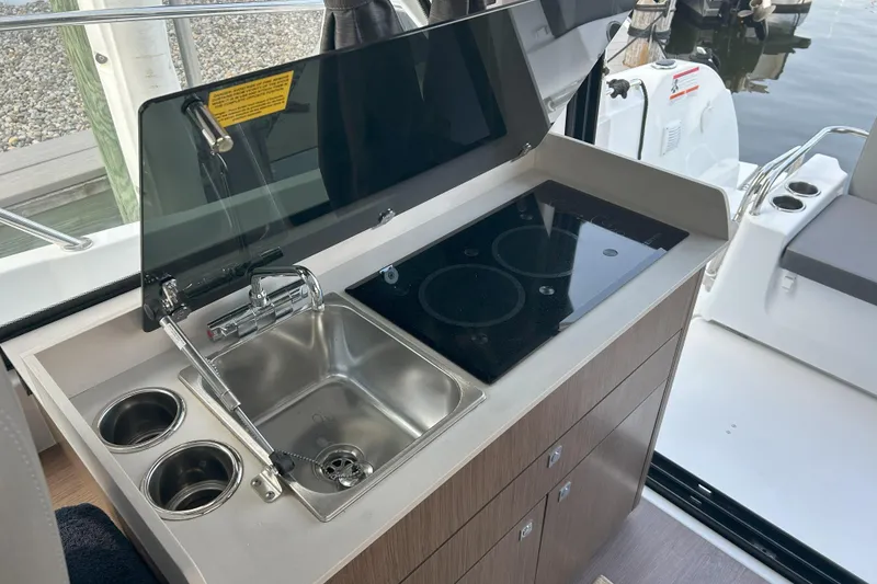 Slide: The Image of 2024 Beneteau Antares 9 kitchen area with sink and stove, dockside view. - 10