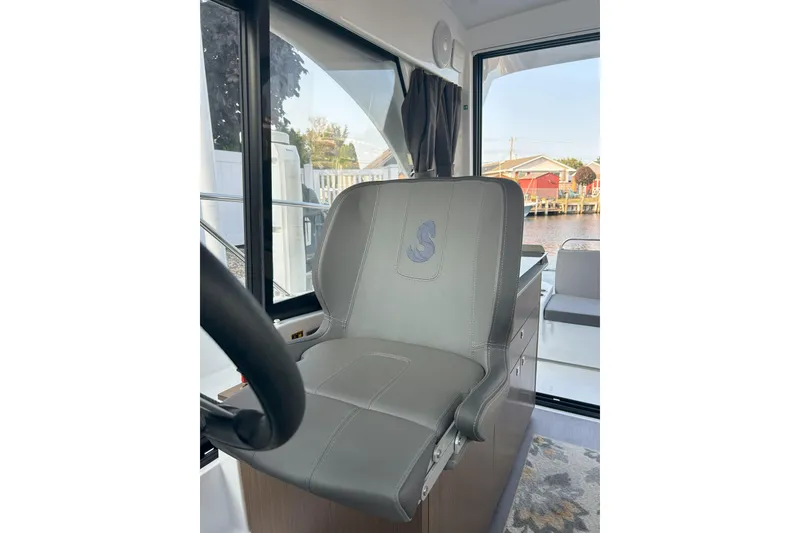 Slide: The Image of Captain's seat in 2024 Beneteau Antares 9 boat interior, featuring sleek design and waterfront view. - 13