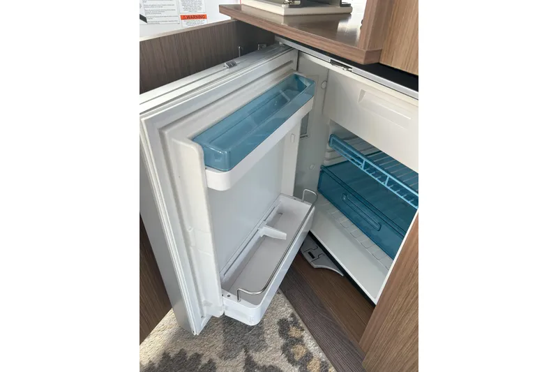 Slide: The Image of Open refrigerator inside 2024 Beneteau Antares 9 boat, showcasing interior shelves and compartments. - 22