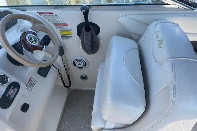 Slide: The Image of 2001 Sea Ray 225 Weekender boat interior with steering wheel and white seating. - 5