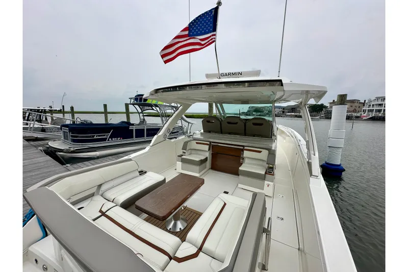 Slide: The Image of 2022 Tiara Yachts 38 LS at dock, featuring spacious seating and American flag. - 10